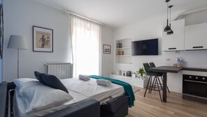 Ein modernes Schlafzimmer mit Bett, Nachttisch und Blick auf die Küche.