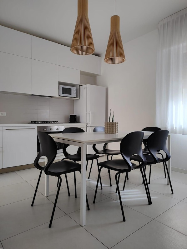 A modern kitchen with white cabinets, a microwave, a stove, and a dining table with black chairs.