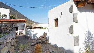 Un patio con un edificio blanco, un muro de piedra y un techo de madera.