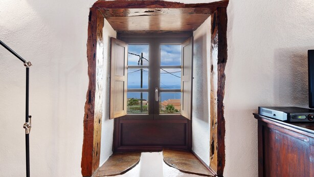 A narrow room with a large window, a wooden cabinet, and a floor lamp.
