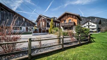 Ein traditionelles Holzhaus mit Balkon, umgeben von einem gepflegten Rasen und einem Holzzaun.