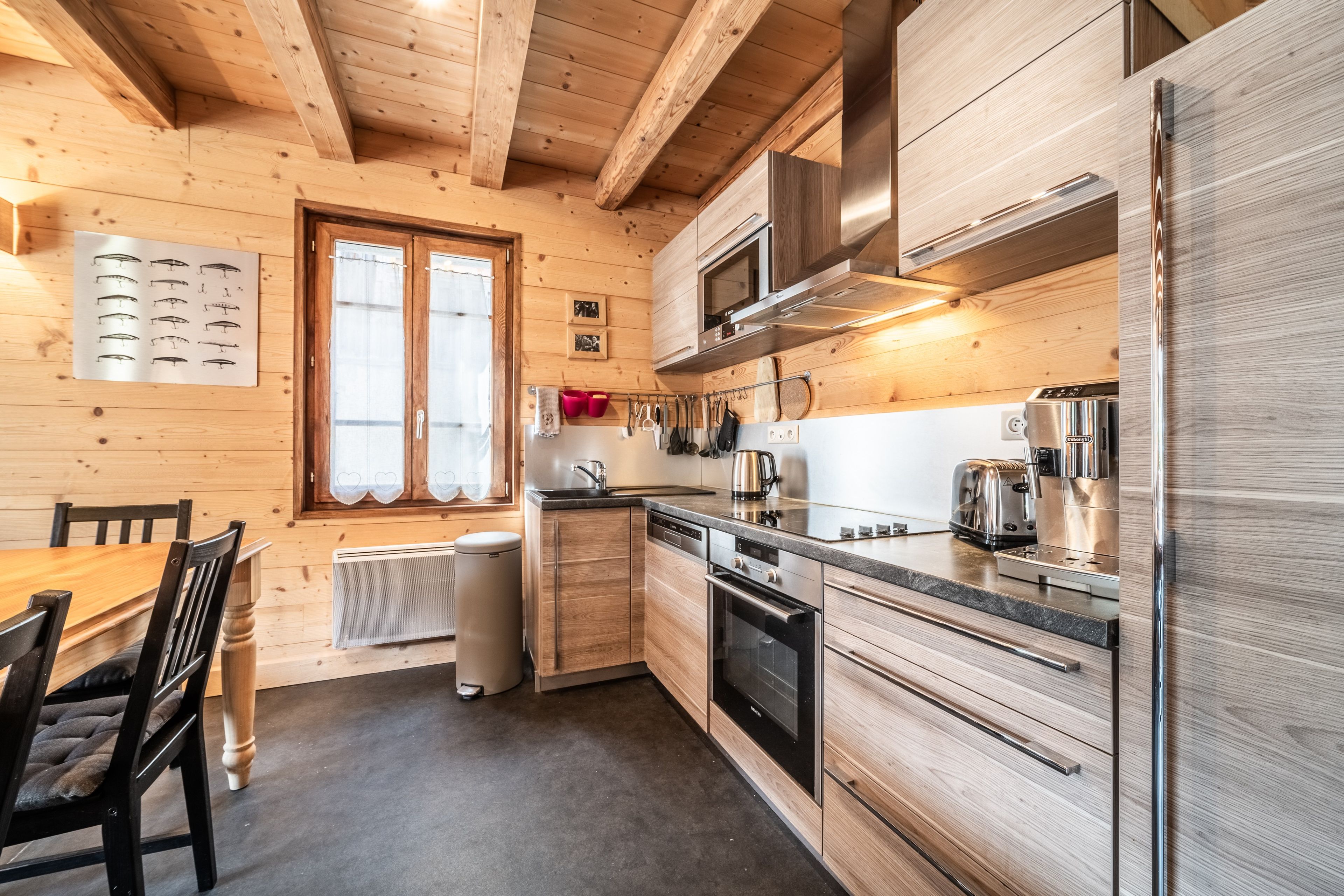 Eine moderne Küche mit Holzwänden, einem Edelstahlkühlschrank, einer Mikrowelle und einem eingebauten Backofen.