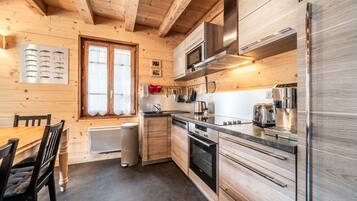 Eine moderne Küche mit Holzwänden, einem Edelstahlkühlschrank, einer Mikrowelle und einem eingebauten Backofen.