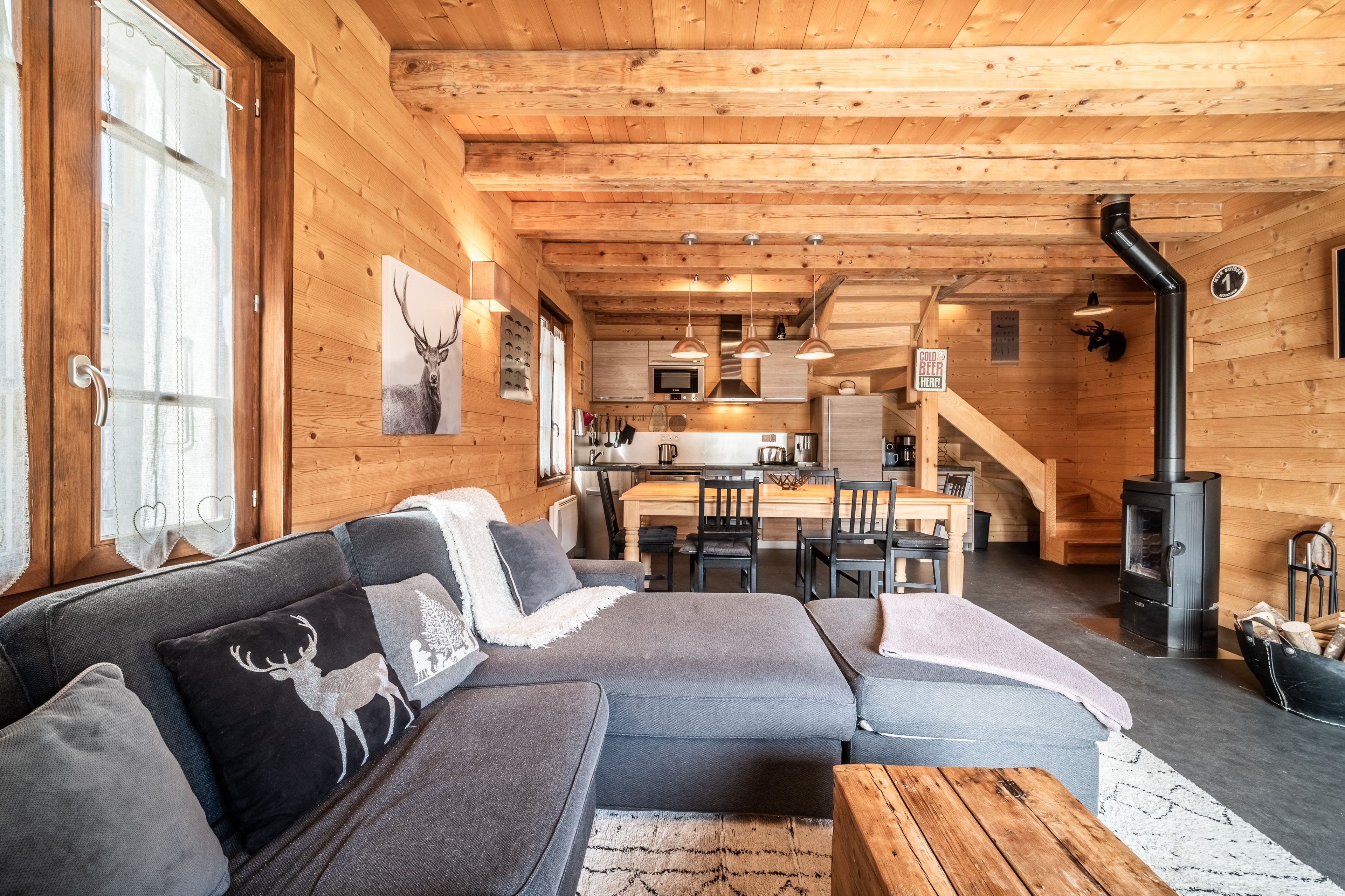 Een knus houten interieur met een bank, een eethoek en een open haard.