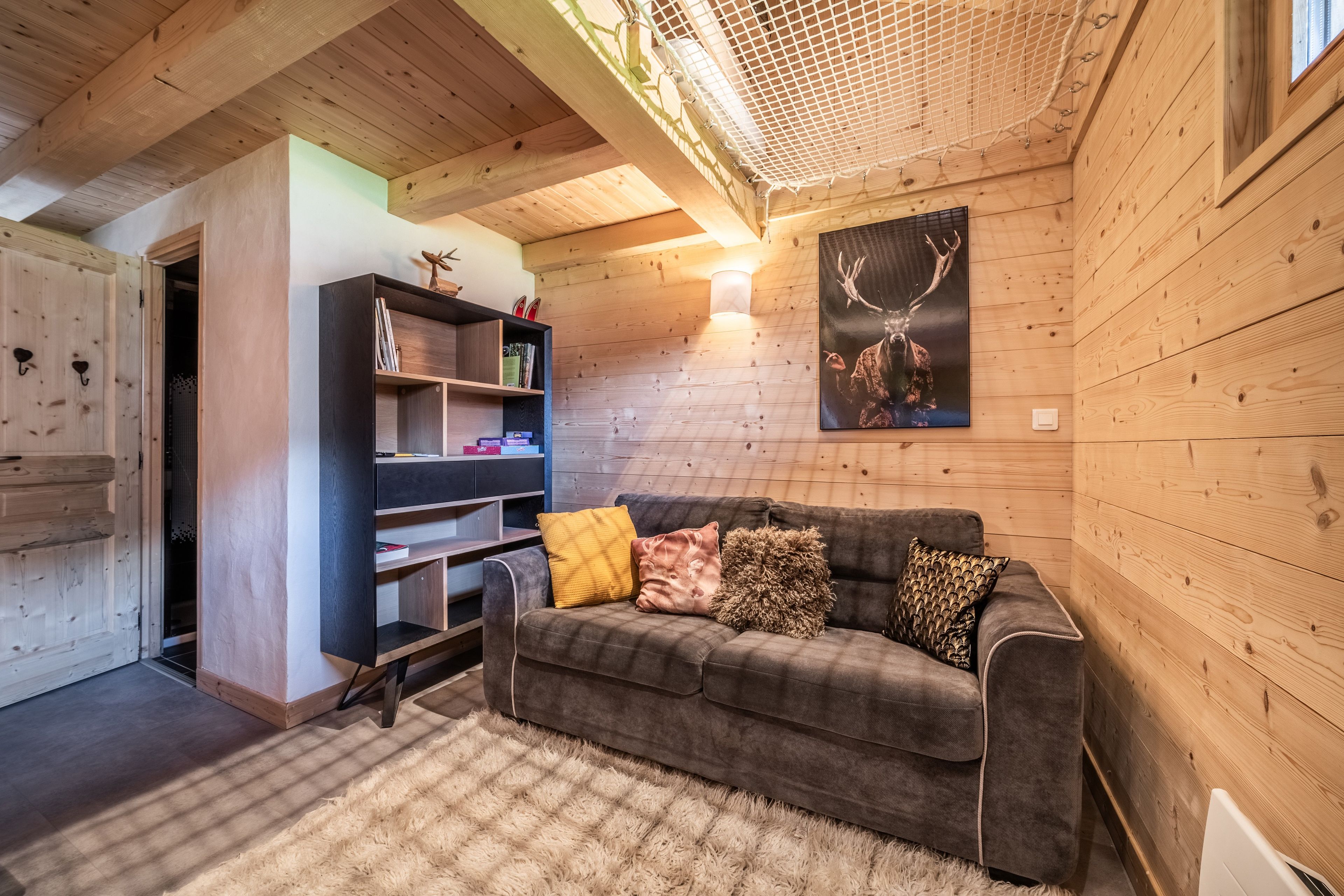 Ein gemütliches Cabin-Interieur mit einer Couch, einem Bücherregal und einer Hirsch-Motiv-Kunst.