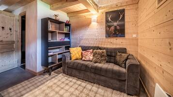 Ein gemütliches Cabin-Interieur mit einer Couch, einem Bücherregal und einer Hirsch-Motiv-Kunst.