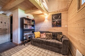 A cozy cabin interior with a sofa, a bookshelf, and a deer-themed artwork.