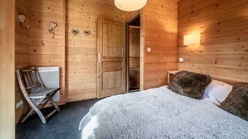 Een houten kamer met een bed, een stoel en een deur.