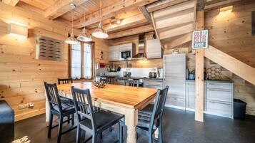 Een houten interieur met een eettafel, stoelen, een keukenhoek, en een bordje waarop 'koud biertje' staat.