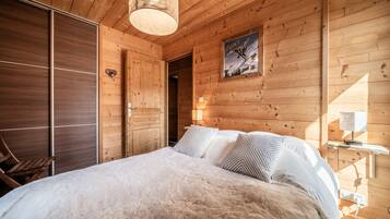 Una habitación de cabaña de madera con una cama, un armario de madera y un cuadro en la pared.