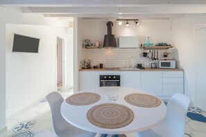 Une cuisine moderne avec des armoires blanches, un four à micro-ondes et une cuisinière. On y trouve une table à manger avec trois sets de table et deux chaises.