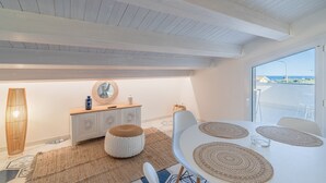 Et moderne interiør med et spiseområde, et hvidt bord og udsigt gennem en glasdør.