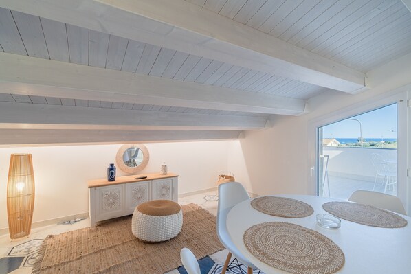 A modern interior with a dining area, a white table, and a view through a glass door.