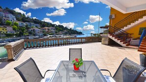 A terrace with a table and chairs, overlooking a coastal town with buildings and boats. - Holiday apartment with air conditioning (Rabac)