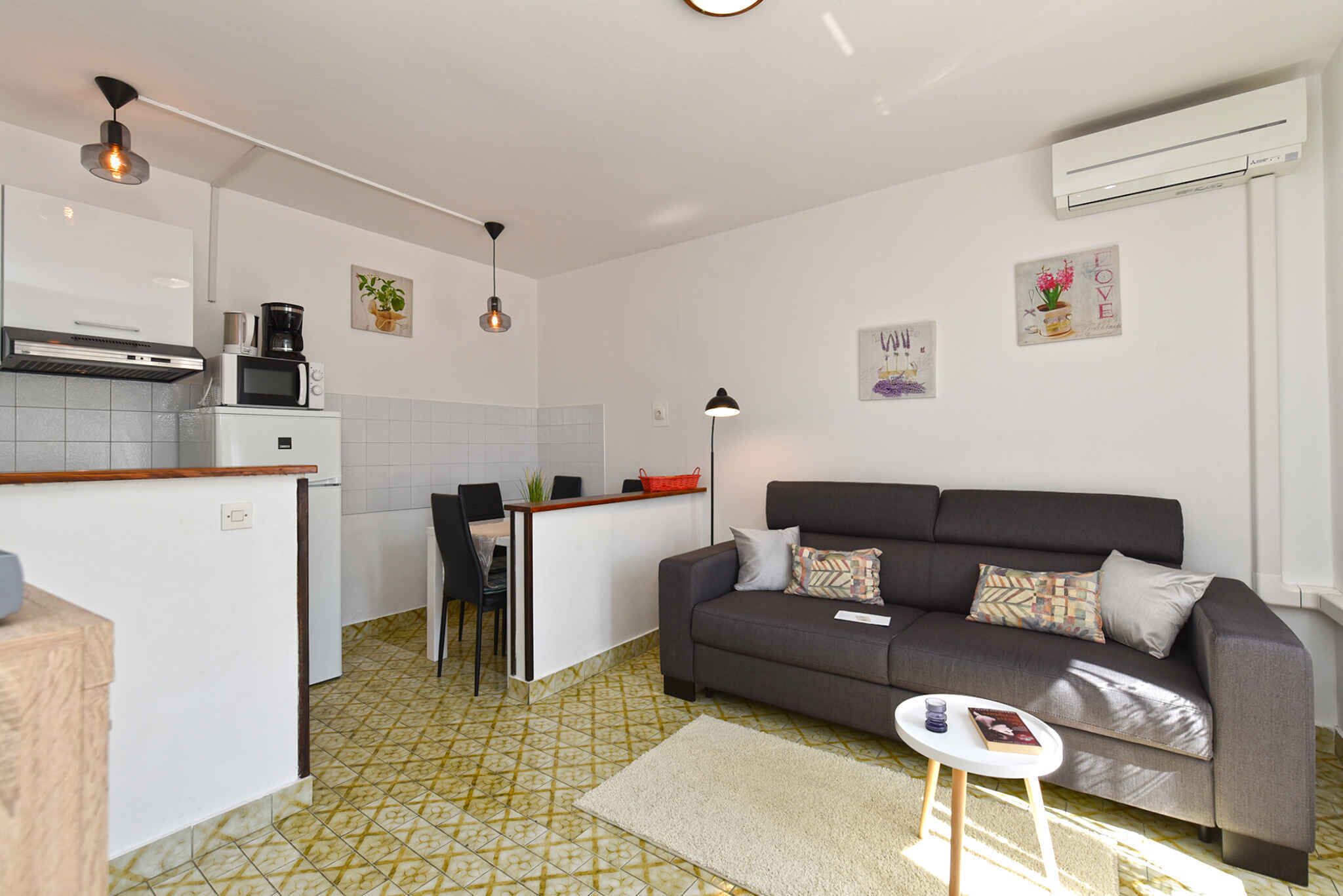 Un espacio habitable compacto con kitchenette, un sofá, una mesita y una cafetera.