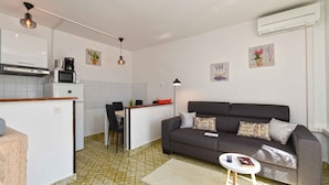 A compact living space with a kitchenette, a sofa, a small table, and a coffee machine. - Holiday apartment with air conditioning (Rabac)