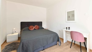 A bedroom with a bed, a desk, a chair, a nightstand, and a lamp. - Holiday apartment with air conditioning (Rabac)