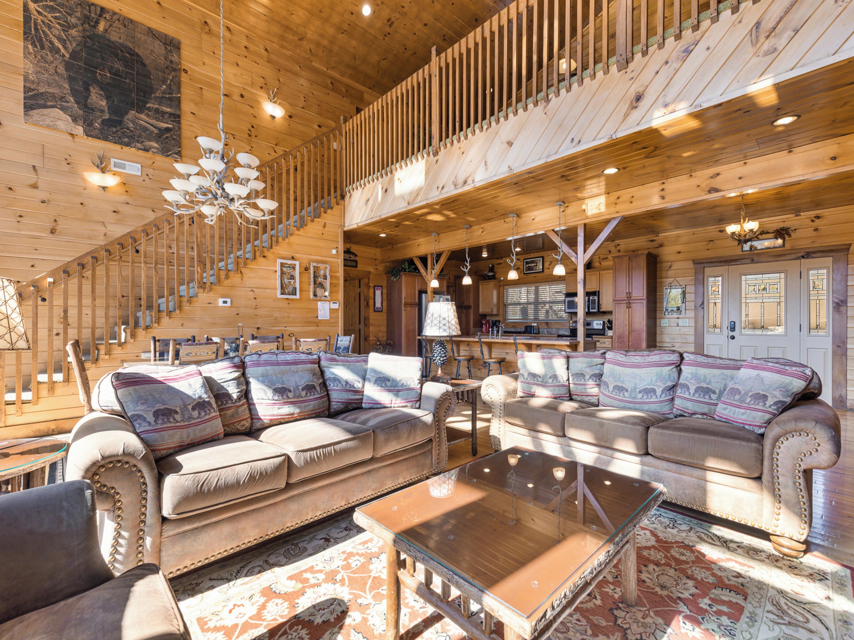 Amplia sala de estar con un sofá grande, una escalera de madera y una zona de cocina.