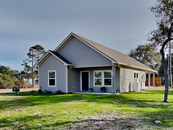 A single-story house with a gabled roof, a front porch with a bench, and a small front yard. - Holiday Hideaway by Miss Kitty’s (Rockport)