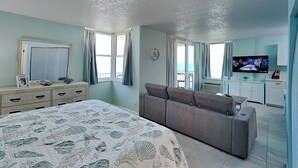 Ein Schlafzimmer mit einem Bett, einer Couch, einem Fernseher und einer Küchenzeile.