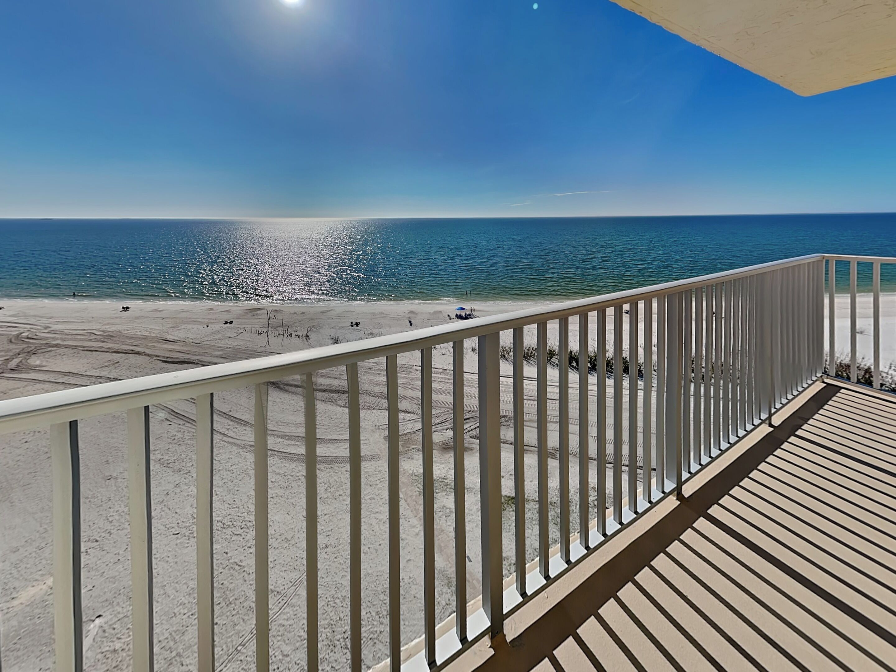 Un balcon avec vue sur une plage et l’océan.