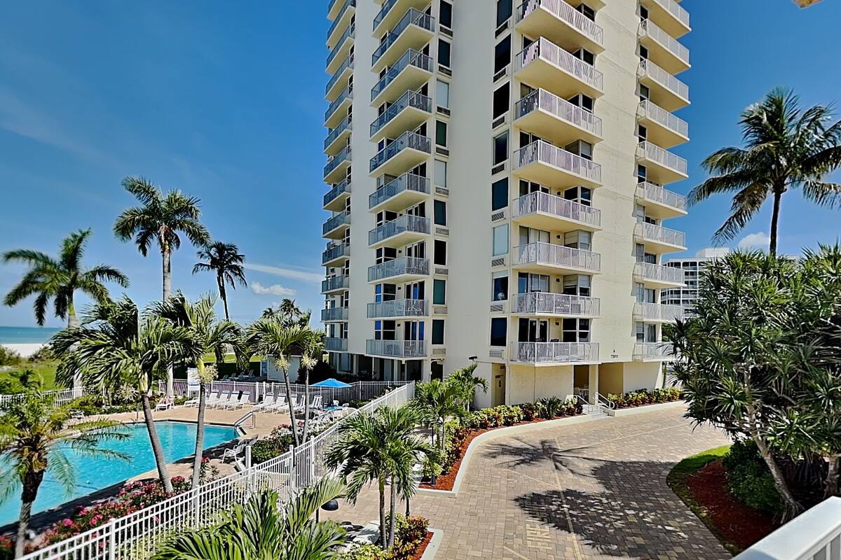 Un hôtel à plusieurs étages doté de balcons, d’une piscine et de palmiers.