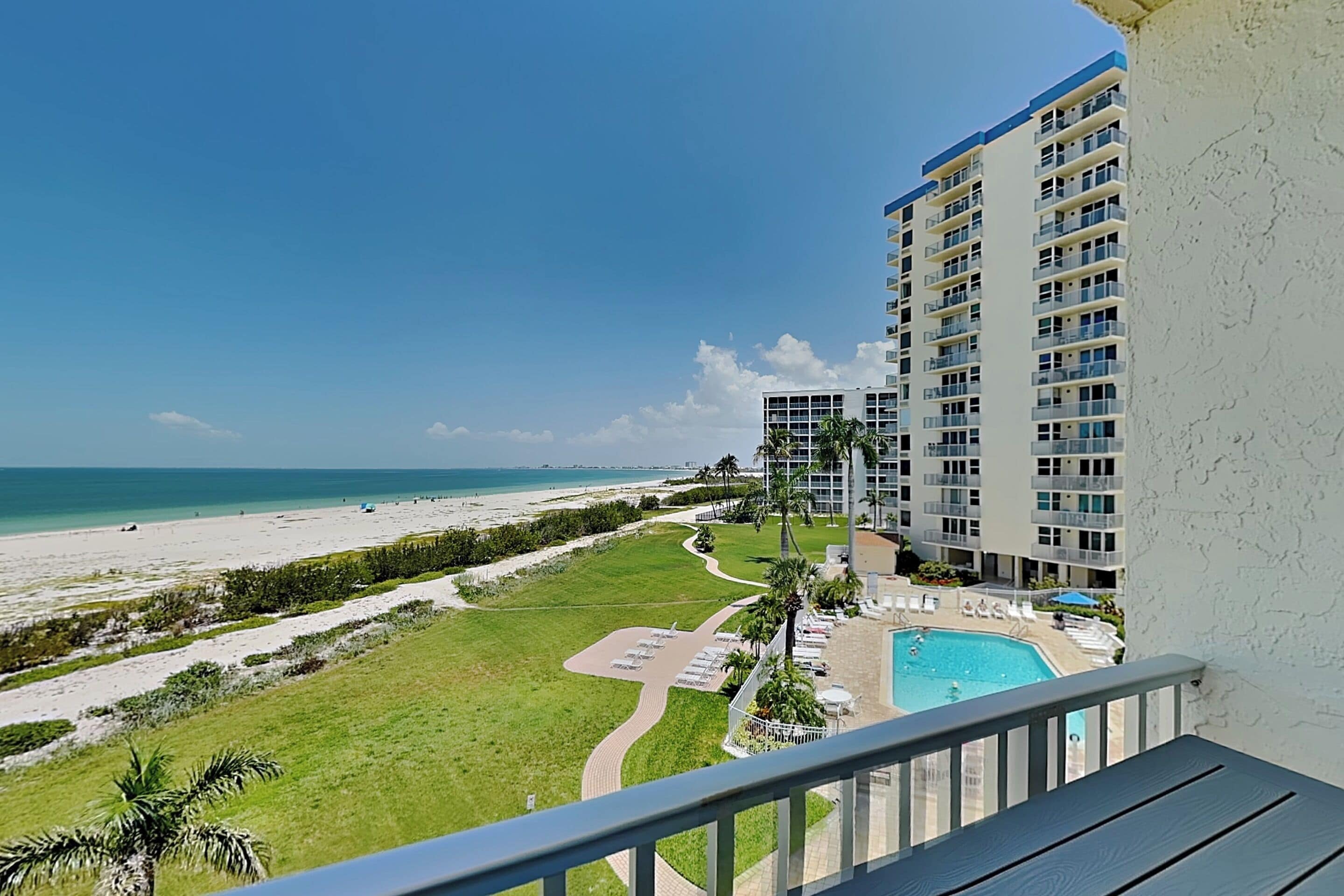 Um hotel moderno com piscina, vista para a praia e um jardim bem cuidado.