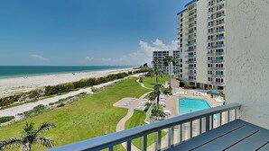 Ein Hochhaus-Hotel mit Pool, Blick auf den Strand und einer gepflegten Grünfläche.