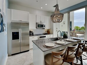 A modern kitchen with stainless steel appliances, a granite countertop, and a large island with bar seating.