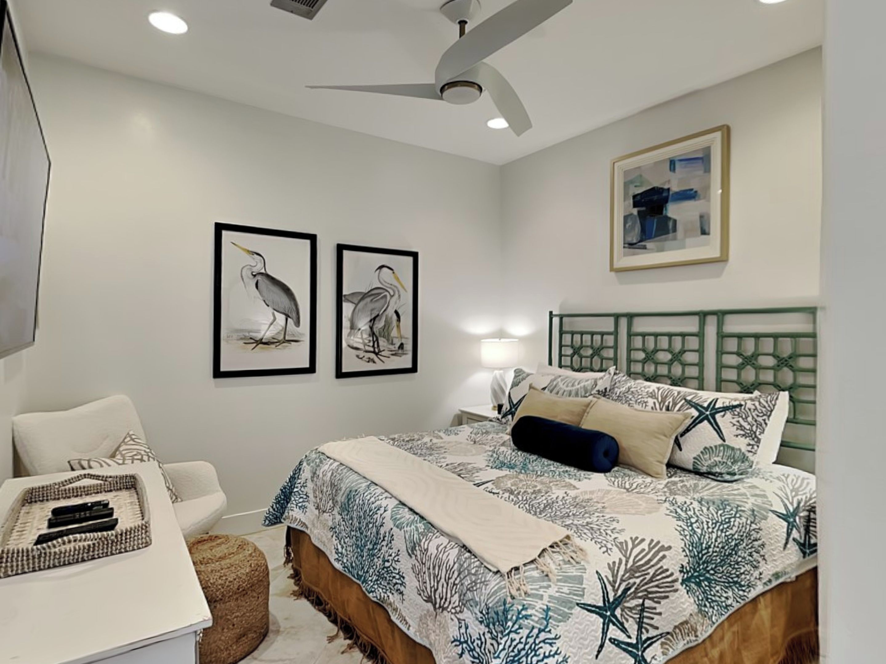 A bedroom with a bed, a desk, a chair, and artwork on the walls.