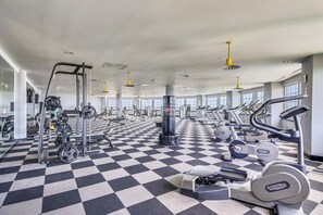 Ein Fitnessstudio mit Schachbrettfußboden, unterschiedlicher Trainingsausstattung und großen Fenstern.