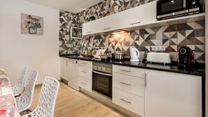 A modern kitchen with geometric patterned backsplash, white cabinetry, and stainless steel appliances. - Cristal VIP Properties by Interhome (Albufeira)