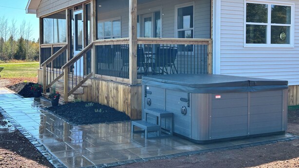 A modern house with a covered porch, a hot tub, and a patio area. - Bliss on the Bay (Birch Hill)