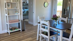 A modern kitchen with a dining area, wooden flooring, white cabinetry, and a built-in bench. - Bliss on the Bay (Birch Hill)