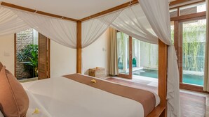 Ein Schlafzimmer mit einem großen Bett, Blick auf einen Swimmingpool und einer Steinwand.