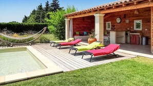 A wooden villa with a pool, outdoor seating, and a hammock.