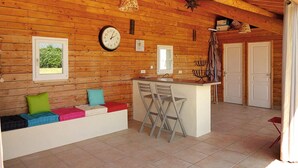 A cozy cabin interior with a wooden interior, a kitchen area with a bar, and a seating area with colorful cushions.