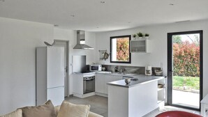 A modern kitchen with a central island, a refrigerator, a microwave, and a stove.