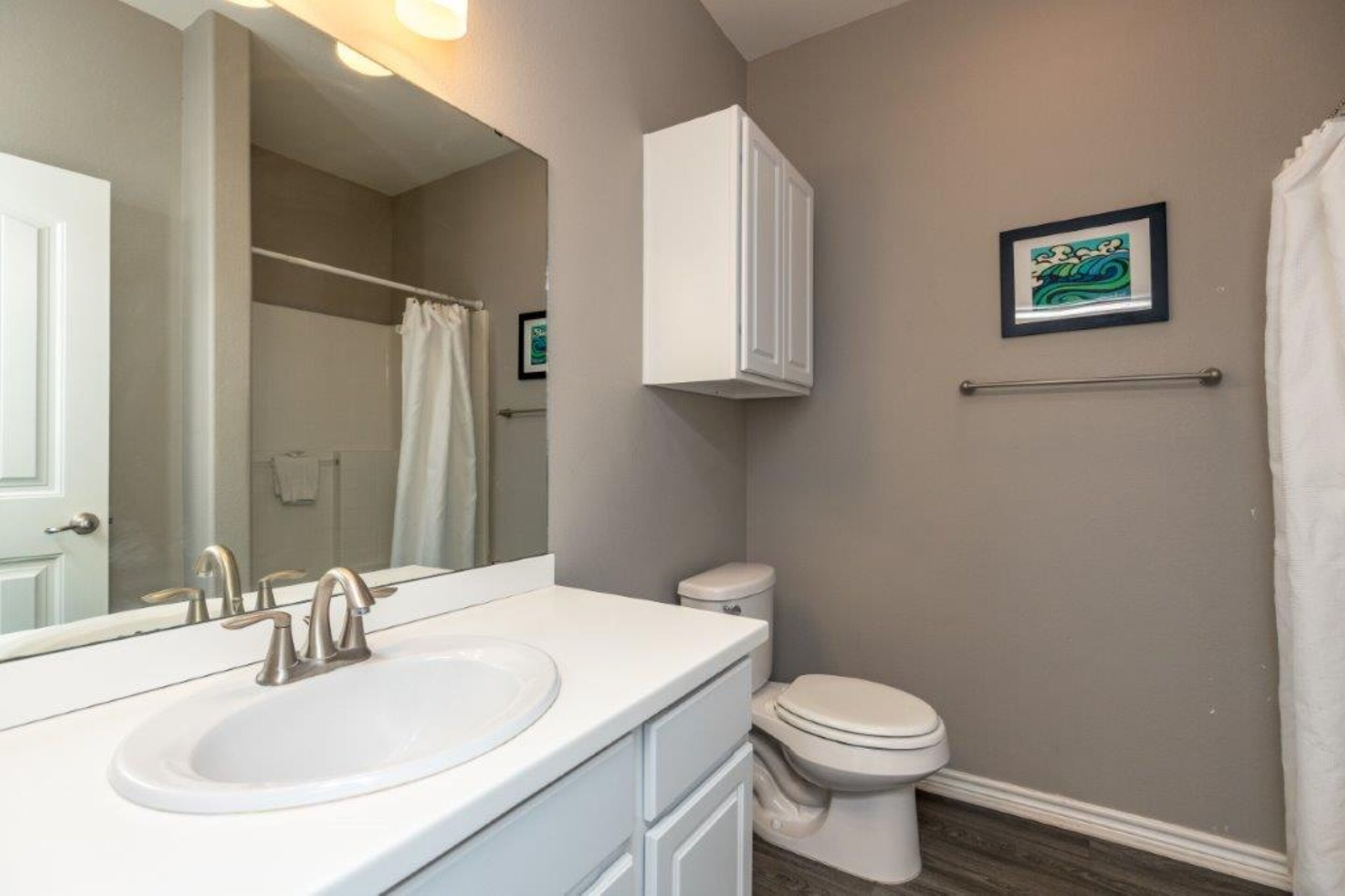 A bathroom with a white sink, a toilet, and a shower curtain.