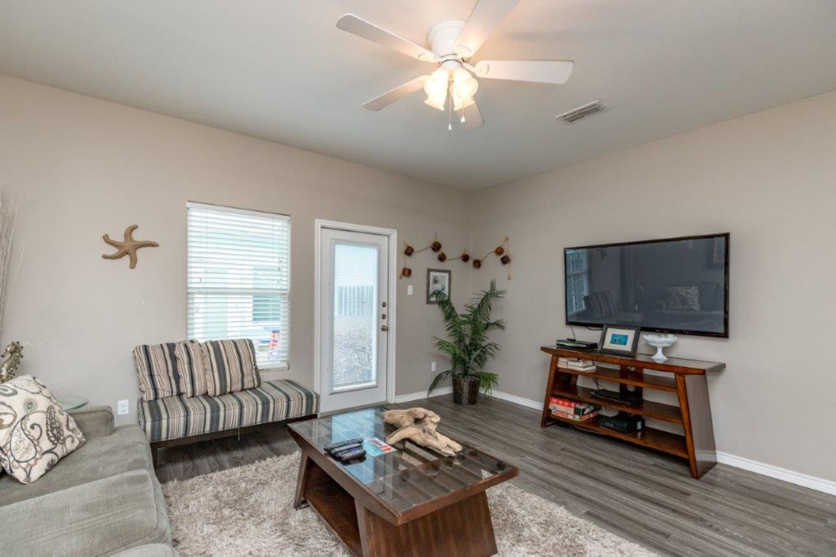 A living room with a sofa, a coffee table, a TV, and a ceiling fan.