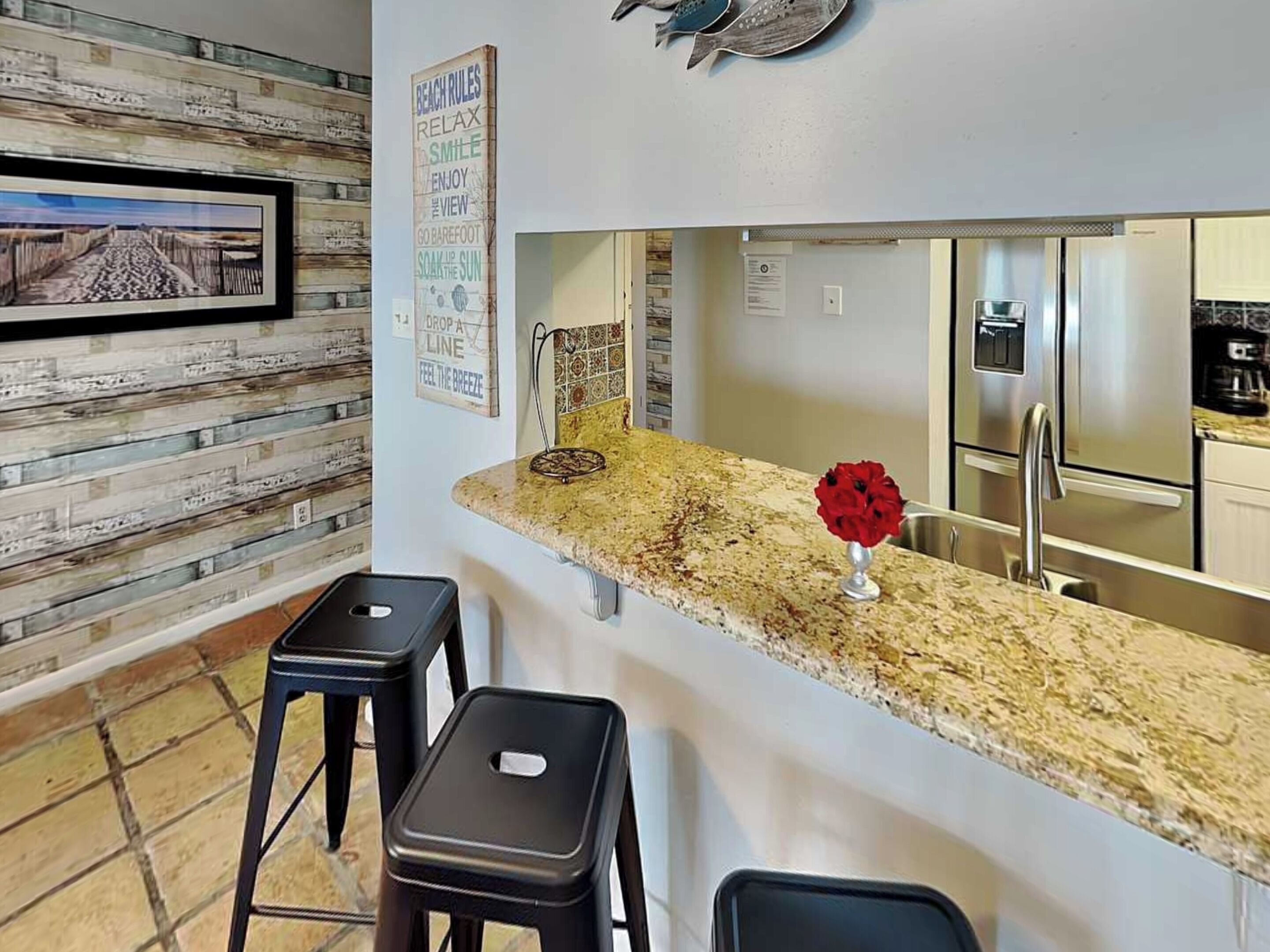 A kitchen with a granite countertop, stainless steel appliances, and a wooden backsplash.