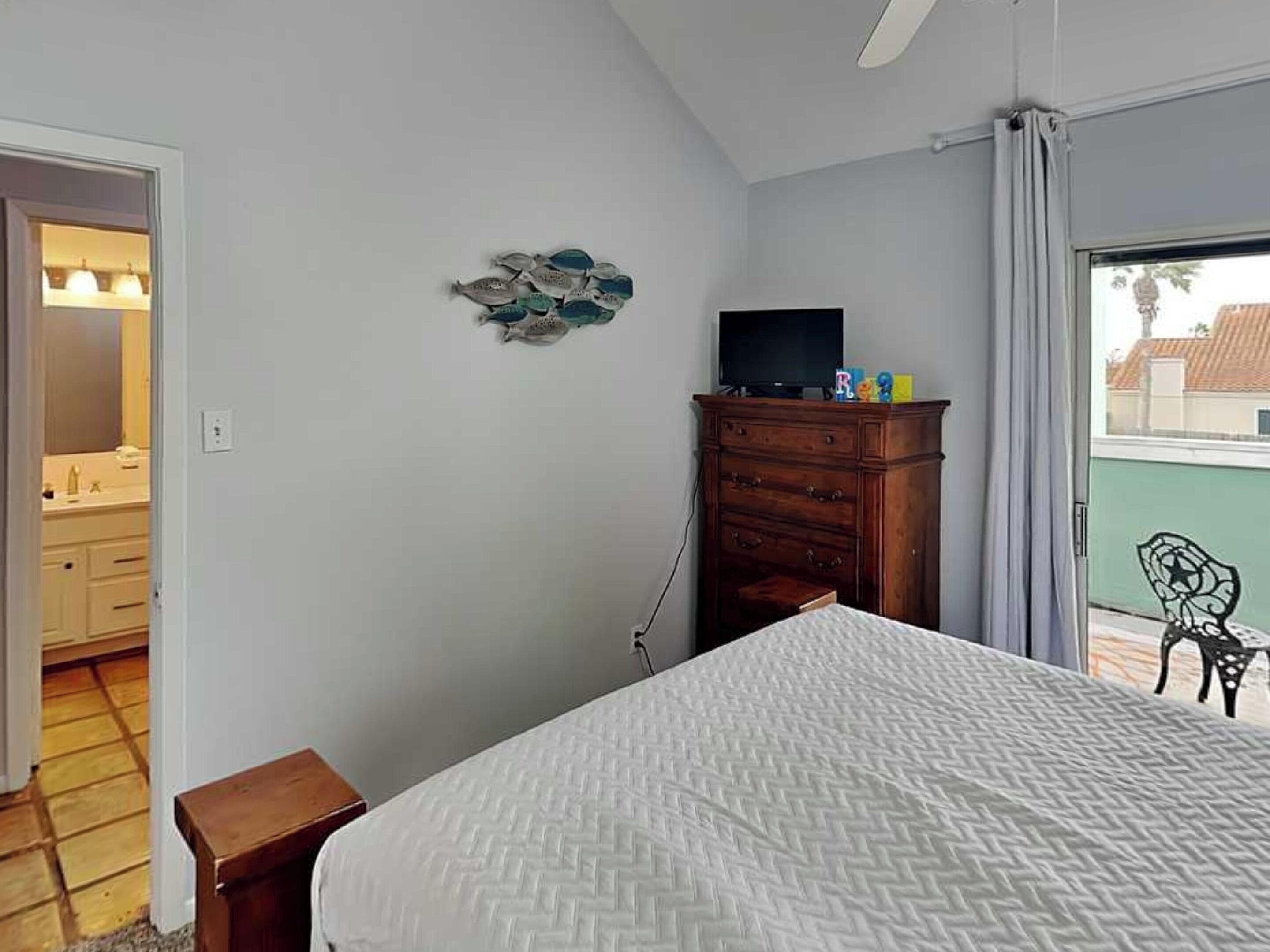 Ein Schlafzimmer mit Bett, Schminktisch, Fernseher und Blick ins Freie.