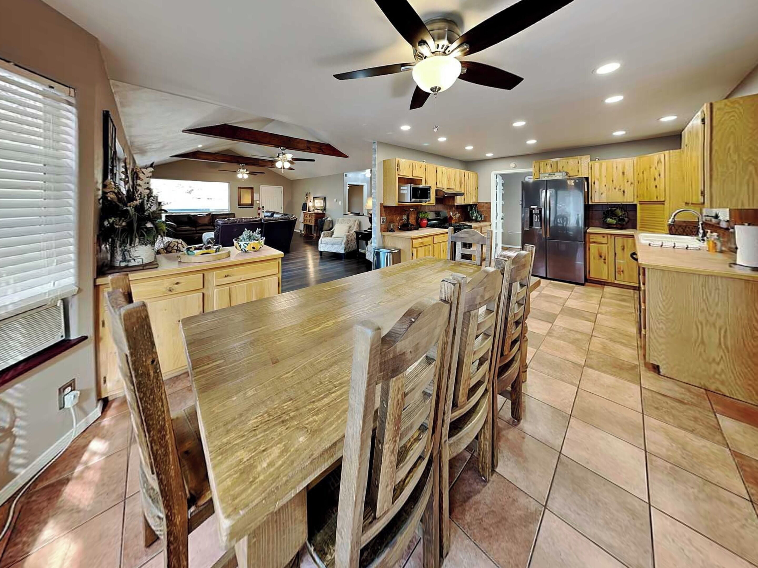 A spacious kitchen with wooden cabinets, a large island, and a ceiling fan.