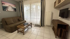 A living room with a sofa, a coffee table, a TV, and a painting on the wall. - Pornichet - Résidence Ker Juliette (PORNICHET)