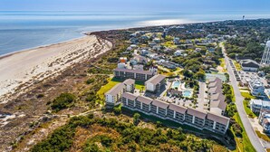 Vista aérea de un pueblo costero con playa, un gran complejo hotelero y una torre de agua.