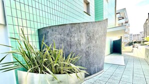 A modern building with a curved concrete wall and a planter with tall green plants.