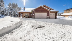 Ein zweistöckiges Haus mit Garage, umgeben von schneebedeckten Bäumen.