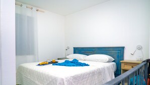 A neatly made bed with white bedding and a blue headboard, a bedside table with a lamp, and a small table with breakfast items. - Freedom Relais Club by Interhome (Massa Lubrense)