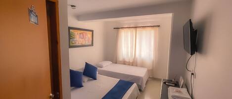 A hotel room with two beds, a television, and a desk with a telephone.