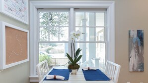 A dining area with a white table, blue placemats, and a potted plant. - Waterfront Willoughby Oasis (Norfolk)